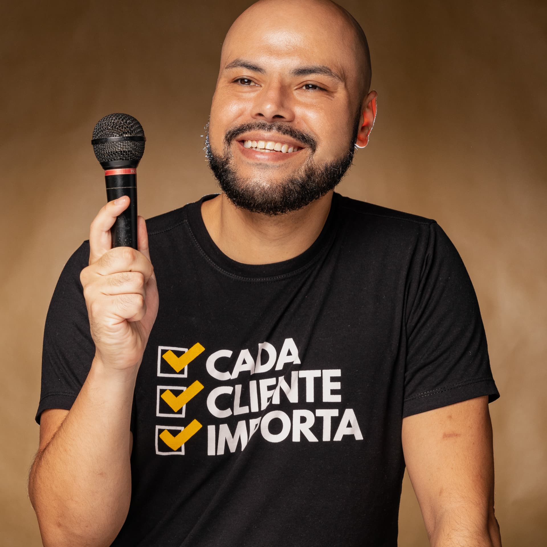 Robson Costa sorrindo com um microfone, vestindo camiseta Cada cliente importa